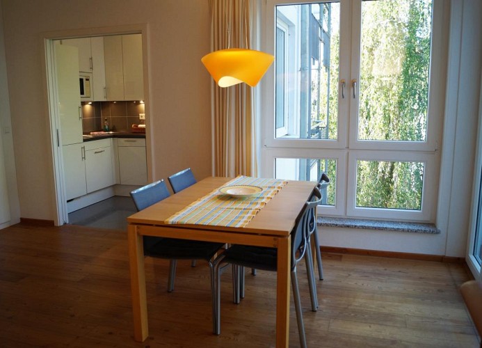 Essbereich an durchgehender Fensterfront mit Blick zur Küche