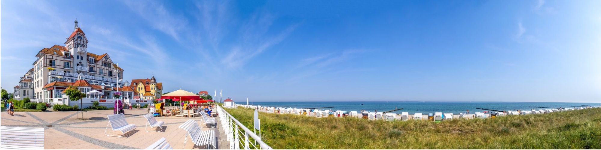 Panoramabild auf eine Strandpromenade vor dem mit Strandkörben belegten Strand der Ostsee
